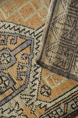 Folded corner of vintage distressed Oushak rug, showing geometric lace pattern with faint foundation.