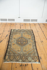 Distressed Oushak rug corner revealing pale burnt orange, antique ivory, and serrated geometric border.