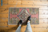 Distressed vintage Oushak rug showing pale rose field and geometric potted plant motifs.