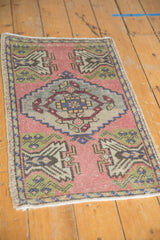 Distressed Oushak rug corner showing pale rose field, green germinating plant motifs.