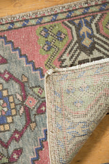 Vintage distressed Oushak rug detail showing worn pale rose, green patterns, and woven reverse.