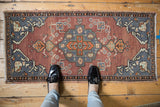 Distressed vintage Oushak rug corner with bronze field, slate gray spandrel, tangerine vinery.