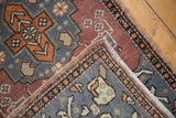 Distressed Oushak rug folded corner, showcasing slate gray, tangerine, bronze plant motifs.