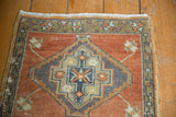 Distressed Oushak rug detail: geometric medallion in burnt orange, oxidized silver, mint green, and beige.