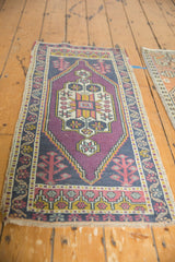 Distressed vintage Oushak rug with geometric medallion, pomegranate motifs, purple, navy, gold tones.