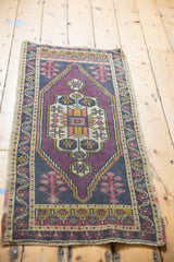 Faded purple, gold, and dark navy tones on a worn Oushak rug corner.