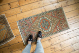 Distressed orange Oushak rug with geometric border and expressive scrolling leaves.