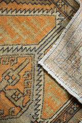 Distressed Oushak rug corner showing worn pile, geometric motifs, and hand-knotted foundation.