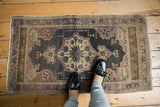 Distressed Oushak rug's ornate center medallion, showing mauve, antique ivory, and dark gray tones.
