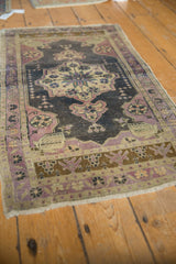 Distressed pile, mauve pinwheel corner design, and bronze border on a vintage Oushak rug.