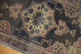 Pinwheel design detail on distressed vintage Oushak rug corner, with mauve, bronze, and antique ivory.