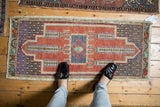 Distressed Oushak rug runner defined by faded cherry red and dusty blue tones.