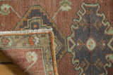 Distressed Oushak rug corner displaying fringe, even pile wear, bronze, and oxidized silver details.