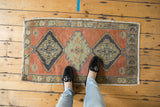 Distressed Oushak rug corner with faded burnt orange field and nuanced charcoal, mint green medallion details.