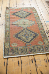Distressed vintage Oushak rug corner with pale burnt orange and geometric charcoal border.