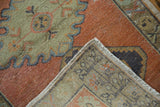 Vintage Distressed Oushak rug corner: worn rust and mint green pile, visible woven foundation.