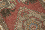 Distressed Oushak rug close-up: textural copper red, beige, and blue geometric field pattern.