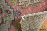 Distressed Oushak rug detail showing even wear, secured edge, and pale rose, silver, green hues.