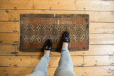 Distressed vintage Oushak rug mat with playful geometric medallions and warm copper tones.