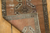 Distressed vintage Oushak rug corner showcasing wear to knot heads and woven foundation.