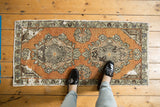 Vintage Oushak runner's distressed texture, terracotta tones, and floral border detail.