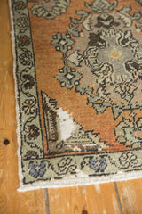 Corner of distressed Oushak runner, featuring time-softened terracotta tones and floral border.
