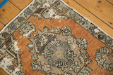 Detail of distressed terracotta and oxidized green Rococo-style patterns on vintage Oushak rug.