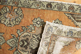 Distressed vintage Oushak rug, folded to show worn terracotta pile, Rococo floral, and reverse foundation.