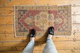 Distressed Oushak rug mat featuring muted floral medallion and geometric spandrels.