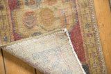 Corner of vintage Oushak rug revealing hand-knotted back and distressed mauve, ivory pile.