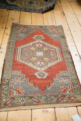Distressed Oushak rug corner revealing rust red field, grey spandrel, and colorful starburst motifs.