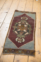 Distressed Oushak rug with aubergine field, central medallion, and worn texture.