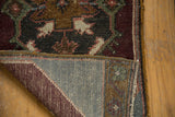 Distressed Oushak rug corner revealing hand-knotted pile, secured side, and woven grey foundation.