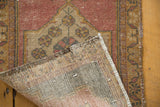 Hand-knotted vintage distressed Oushak rug, curled to show foundation and worn pile.