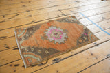 Distressed Oushak rug mat displaying central Rococo-inspired medallion and vibrant fuchsia accents.