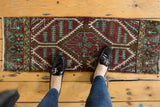 Upper left corner of distressed Oushak runner showcasing geometric patterns in aubergine, mint, and bronze.