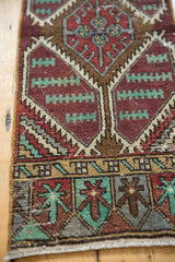 Distressed Oushak rug end border with stylized floral squares in brick red, mint, and bronze.