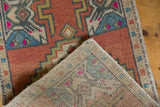 Distressed Vintage Oushak rug corner, showcasing textured brick red pile and sturdy hand-knotted back.