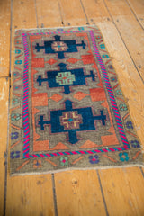 Upper right corner of a vintage distressed Oushak rug, featuring geometric navy medallion and fuchsia border.