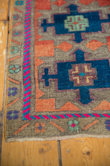 Distressed Oushak rug corner showing fuchsia and sky blue geometric border.