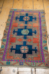 Geometric relief and fuchsia border on a distressed vintage Oushak rug mat with even pile wear.