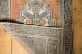 Distressed Oushak rug's apricot pile texture and hand-knotted reverse foundation.