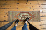 Distressed Oushak runner, highlighting its rams horn medallion and geometric diamonds, shown with feet.