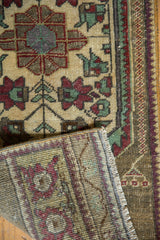 Distressed Oushak rug pile showing exposed foundation, ivory, green, wine red geometric motifs.
