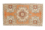 Distressed Oushak rug with faded tangerine orange and muted medallion, featuring geometric plant motifs. 1'7