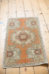Distressed Oushak rug corner in pale tangerine and beige, showing intact side selvage.
