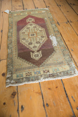 Distressed Oushak rug detail showing geometric stepped border in aubergine and sand.