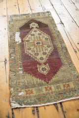 Distressed Vintage Oushak rug, geometric medallion in aubergine, sand, with visible foundation.