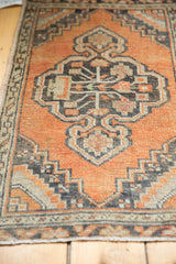 Distressed terracotta Oushak rug, close-up of low pile, charcoal and ivory medallion.