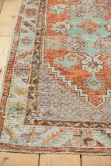 Distressed pile texture of a vintage Oushak rug with brick red and mint green geometric patterns.